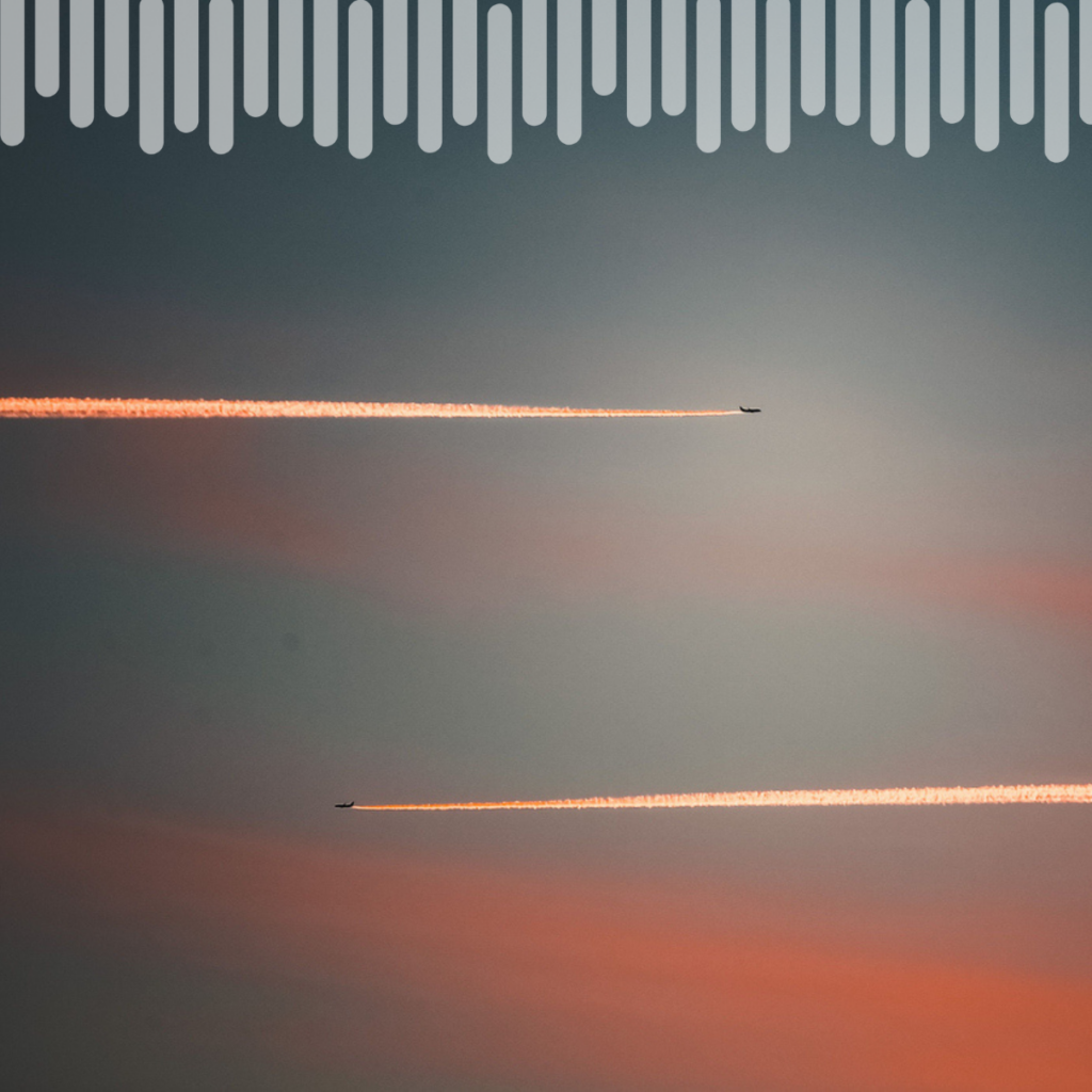 Deux avions laissent derrière eux des traînées lumineuses dans un ciel aux teintes pastel au coucher du soleil ; l'un vole plus haut que l'autre et les deux sont orientés dans des directions opposées.