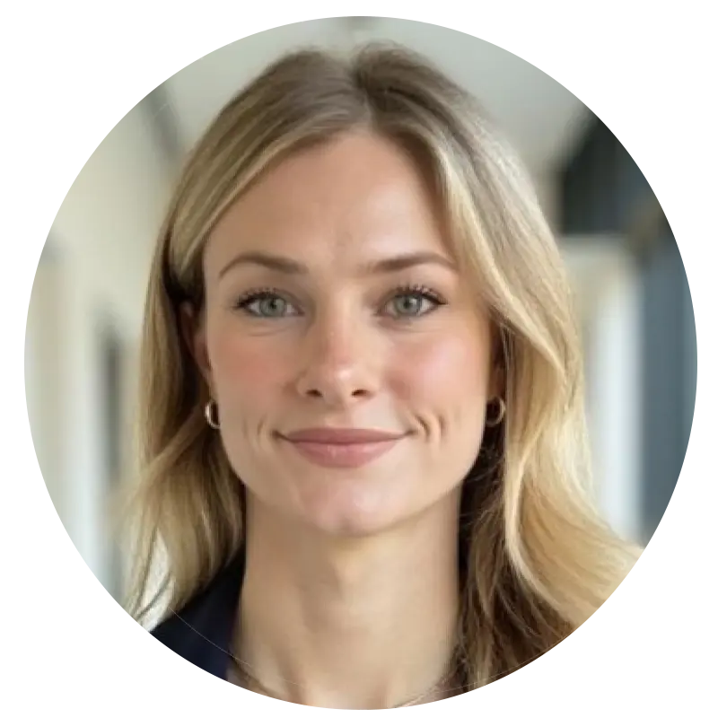 Portrait en buste d'une femme blonde souriante, vêtue d'un blazer foncé.